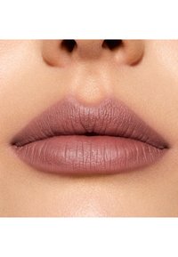 Lèvres mate couleur rose poussiéreux avec une texture visible et une forme définie. Teint naturel autour de la bouche, mettant en valeur la couleur des lèvres.
