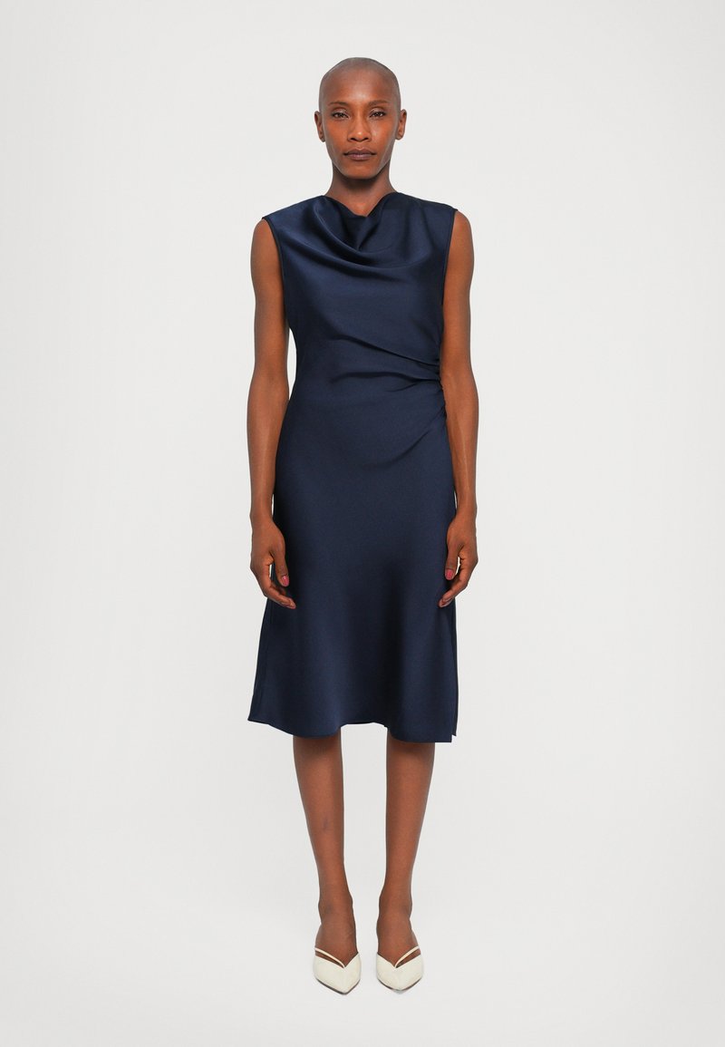 Rochie satinată de culoare bleumarin, cu decolteu drapat, design fără mâneci și detaliu din țesătură răsucită la talie, curgând până la un tiv mediu deasupra gleznelor.