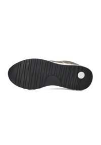 Semelle d'une chaussure avec une surface en caoutchouc noir texturée et des reliefs profonds pour une meilleure adhérence, dotée d'un accent blanc circulaire près du talon.