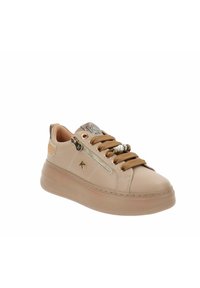 Zapatilla de cuero beige con suela gruesa, cremallera lateral, cordones marrones con cuentas decorativas y logotipo metálico de la marca en el lateral.