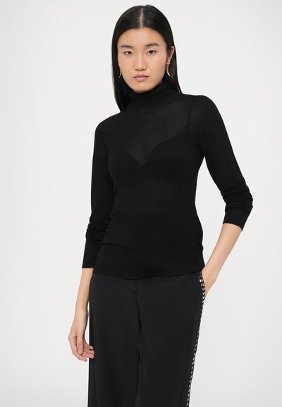 Mustast kerge materjaliga silmkapuuvillane ülaosa, millel on pikad varrukad ja keha järgiv lõige koos peene kaeluse detailiga.