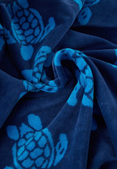 Σκούρο μπλε ύφασμα με ανοιχτόχρωμα μπλε σχέδια χελωνών, διπλωμένο για να αναδεικνύει την υφή και το απαλό, αφράτο υλικό.