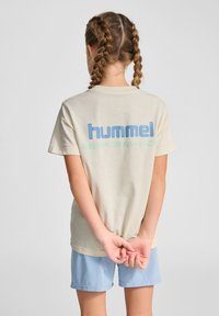 Beige bomuld t-shirt med korte ærmer, prydet med stort blåt og grønt "hummel PERFORMANCE" tekst trykt på ryggen.
