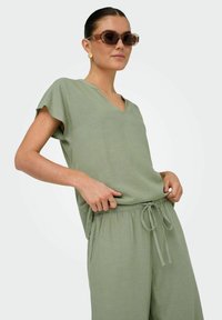 Ljust grön, lin-blandad topp med V-ringning och korta ärmar, i kombination med matchande byxor med dragsko och sidofickor.