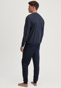 Navy pyjamastel met een bedrukt langemouwen top met een ronde halslijn en effen broek met elastische boorden. Gemaakt van zachte, lichte stof.