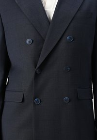 Blazer bleu marine à double boutonnage avec un motif à carreaux subtil, doté de boutons bleus, de revers crantés et d'une poche poitrine simple.