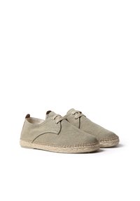 Scarpe verdi in tela con design a lacci, suola in giuta stile espadrille e dettagli marroni sul tallone. Tessuto texturizzato e dettagli cuciti.