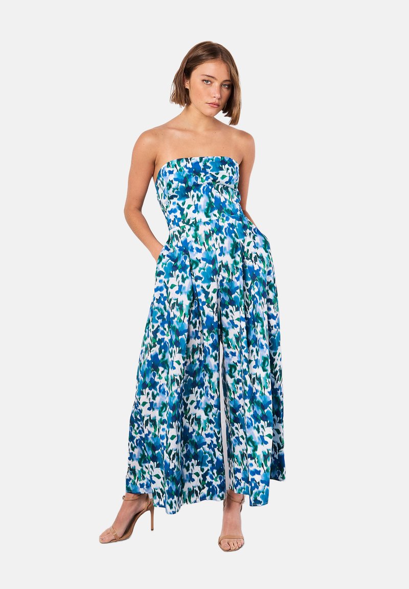 Strapless maxi dress in blue and green abstract print. Flowy fabric with side pockets and a fitted bodice, featuring a full skirt with slits.