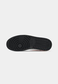 Čierna gumená podrážka tenisiek s cirkulárnymi a horizontálnymi vzorom; obsahuje branding Nike; čistý, textúrovaný povrch so celkovým robustným vzhľadom.