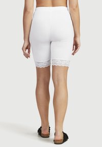 Witte katoenen shorts met een aansluitend ontwerp, voorzien van een gegolfde kantafwerking aan de onderrand. De shorts hebben een elastische tailleband voor comfort.