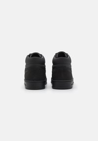 Svarte høye sneakers laget av glatt l�ær og semsket skinn, med polstret krage og gummisåle med subtile merkinger på hælen.