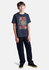 Donkerblauw graphic t-shirt met kleurrijke cartoonontwerpen, gecombineerd met zwarte broek en zwarte schoenen met gumzolen.