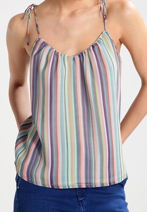 Ärmelloses Top mit dünnen Bindeträgern, versehen mit mehrfarbigen vertikalen Streifen und Chevron-Mustern, getragen zu blauen Jeans aus Denim.