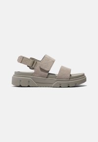 Beige semišové sandály s nastavitelným páskem, silnou texturovanou podešví a minimalistickým designem. Obsahují suchý zip a otevřenou patu.