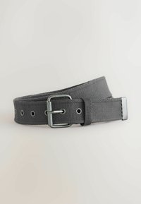 Ceinture en tissu tissé gris foncé avec boucle en métal et plusieurs trous, légèrement enroulée sur un fond clair.