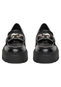 Juodi odiniai loaferiai su masyviu, tekstūruotu padu, turintys blizgią sidabrinę grandinę priekyje ir klasikinį siuvinėjimo dizainą.