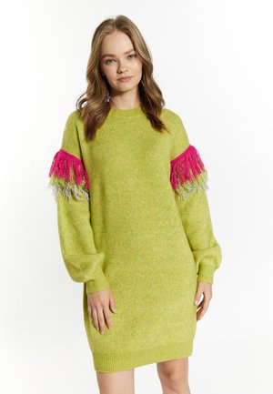 Gebreide jurk in felgroen met lange pofmouwen. Beschikt over rozekleurige en multicolore franjes op de schouders. Ribgebreide manchetten en zoom.