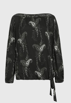 Blouse noire à épaules dénudées avec motif paisley blanc, manches longues, ourlet élastique et détail noué sur le côté sur fond uni.
