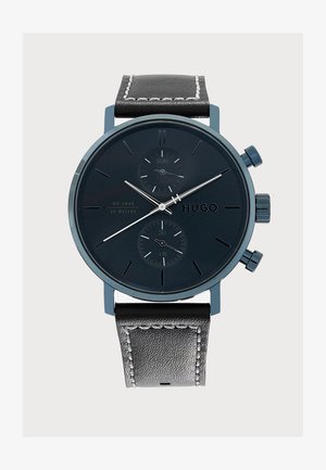 Montre-bracelet noire Hugo avec bracelet en cuir, deux sous-cadrans affichant le jour et la date, aiguilles argentées et index horaires minimalistes sur un cadran sombre.
