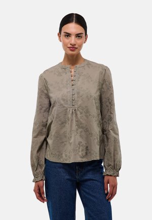 Blouse kaki à manches longues, col rond et patte de boutonnage. Présente des broderies florales et des poignets froncés, fabriquée en tissu léger.