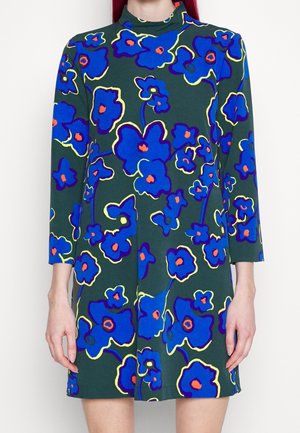 Dark green dress with long sleeves and bright blue floral pattern outlined in yellow and orange, worn by person with red hair.