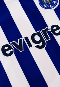 Blauwe en witte gestreepte trui van stof, met een groot zwart tekstlogo en een rond embleem op de bovenlinkerzijde.