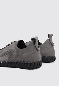 Zapatillas de ante gris con diseño perforado, suela de goma negra y detalles únicos en los cordones. Cuenta con tiradores en el talón para facilitar su uso.