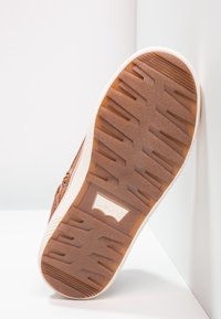 Hnědá teniska s texturovanou gumovou podrážkou, která má decentní logo Levi's. Podešev má cik-cak vzor pro lepší přilnavost a trakci.