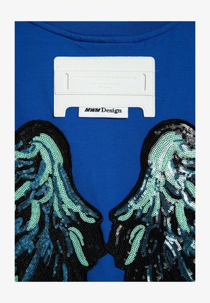 Camiseta de algodón azul con diseños de alas bordados con lentejuelas en aqua y negro. Etiqueta de tela blanca con la marca "MWM Design" en el cuello.