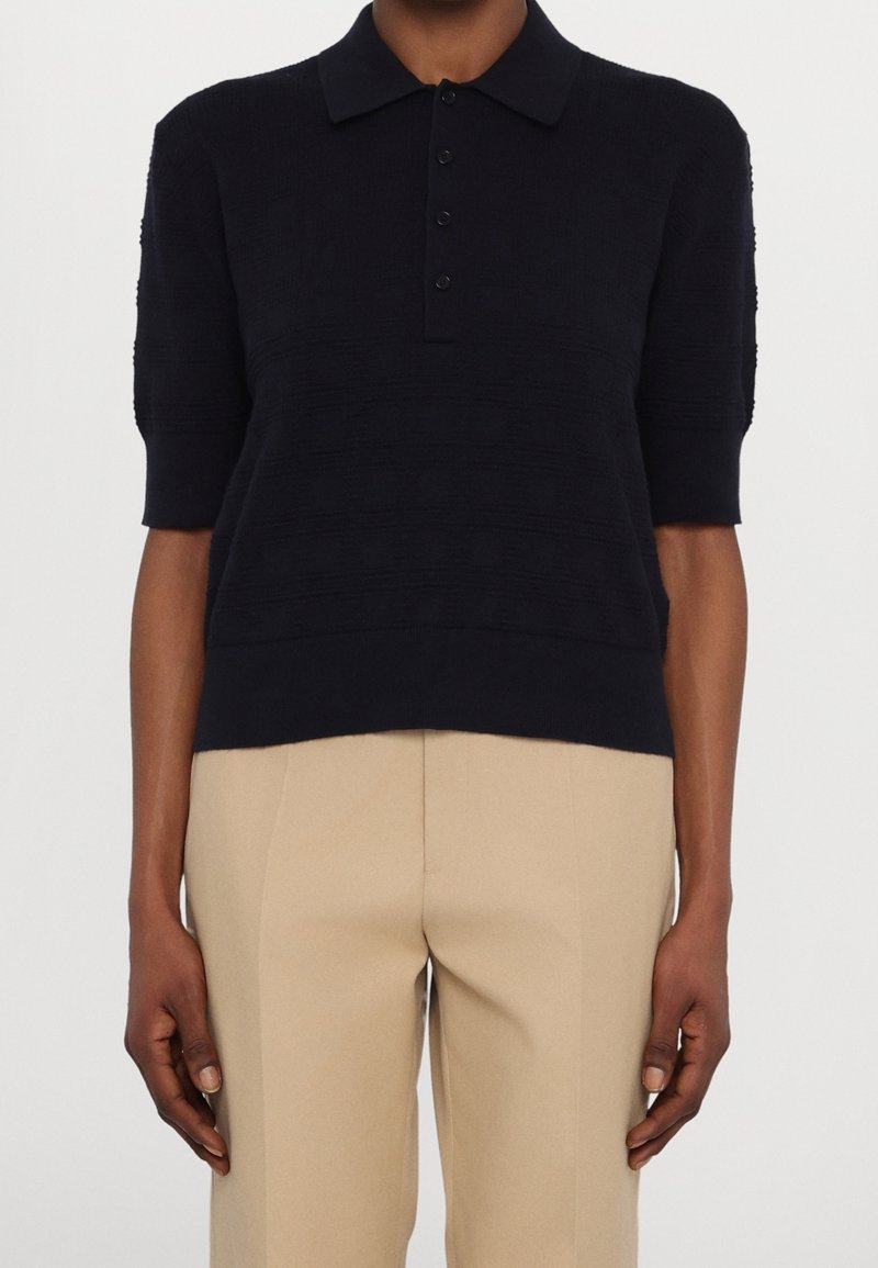 Maglione polo blu navy con maniche corte, motivo a rilievo e orlo a coste, caratterizzato da un colletto classico e chiusura con cinque bottoni.