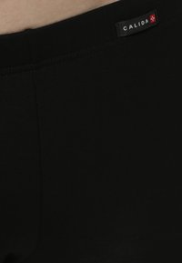 Pantaloni corti neri in cotone con una texture liscia, dotati di un'etichetta CALIDA in vita. Il design è aderente con cuciture minime.