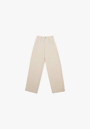 Calças largas bege com pregas na cintura, apresentando bolsos laterais e um design sem costuras, feitas de um tecido leve.