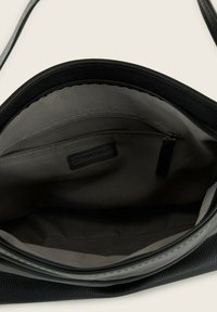 Interno di una borsa a tracolla in pelle nera con texture liscia, tasca con zip e fodera in tessuto di un colore grigio chiaro a contrasto.