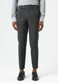 Grijze op maat gemaakte broek met een strak ontwerp, met een gladde textuur, riemlussen en een sluiting met knopen aan de voorkant. Geaccentueerd door scherpe vouwen.