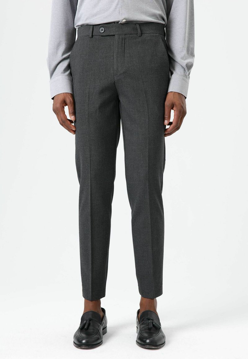 Grijze op maat gemaakte broek met een strak ontwerp, met een gladde textuur, riemlussen en een sluiting met knopen aan de voorkant. Geaccentueerd door scherpe vouwen.