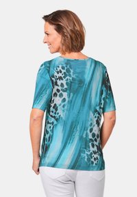 T-Shirt mit kurzen Ärmeln in Türkis mit abstraktem Muster in Blau- und Schwarztönen, runder Ausschnitt und glatter Textur. Mit Leo-Print-Details akzentuiert.