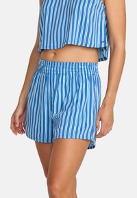 Μπλε σορτς με λευκές κάθετες ρίγες, διαθέτοντας ελαστική μέση και πλευρικές σχισμές για ευκολία στην κίνηση. Ελαφρύ ύφασμα, casual σχεδιασμός.