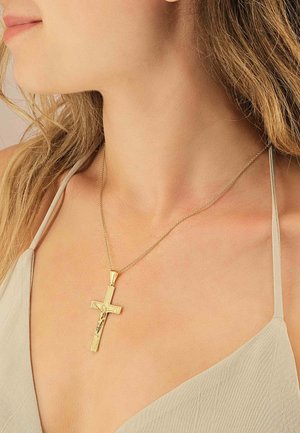 Goldkreuz-Anhänger-Halskette an einer dünnen Kette, mit einem strukturierten Design und einer Figur. Der Hintergrund ist neutral und weich beleuchtet.