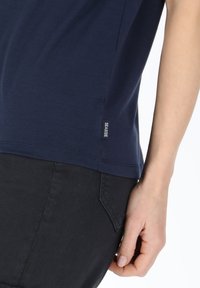 Mörkblå bomullst-shirt med korta ärmar, sidosemsmärke och slät textur, kombinerad med svarta byxor med bakficka.