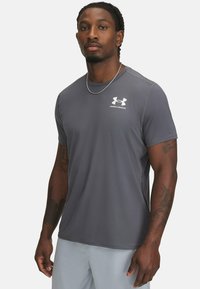Harmaa urheilupaita lyhyillä hihoilla, valmistettu kevyestä materiaalista. Rinnassa valkoinen Under Armour -logo. Sileä rakenne.