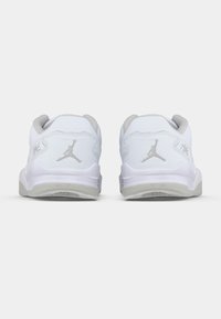 Ζευγάρι λευκών χαμηλών αθλητικών παπουτσιών με γκρίζες σόλες και λογότυπα Jumpman στις φτέρνες, υπό γωνία απ�ό πίσω, σε απλή λευκή φόντο.