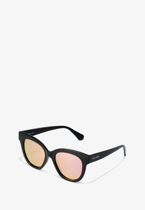 Lunettes de soleil noires avec une forme large en œil de chat. Dotées de verres réfléchissants rose et d'une texture lisse. Logo de la marque sur la branche.