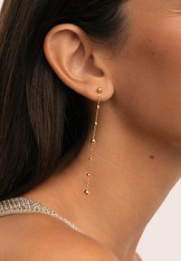 Pendientes de oro colgantes que presentan una cadena con bolas redondas suaves alternas, exhibiendo un diseño delicado y alargado.