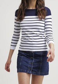 Marineblå och vit randig långärmad topp i kombination med en denimkjol med knappar fram. Mjuk tyg, figursydd design och ribbade detaljer vid halsringningen.