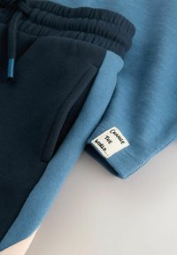 Baumwollmischung Jogginghose mit einem Farbblockdesign in Marineblau und Hellblau, elastischem Bund und einem eingenähten Etikett mit "VERÄNDERE DIE WELT."