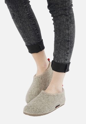 Grå filt slippers med en blød tekstur, med et lavskåret design og en kontrasterende rød accent på hælen, parret med mørke jeans.