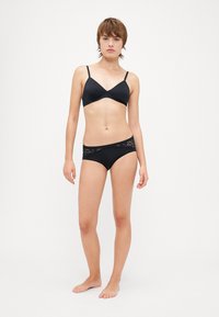 Black lingerie set featuring a simple bralette with thin straps and matching bikini-style briefs with lace accents. Smooth fabric texture.