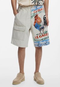 Khaki cargo šortky s elastickým pásom, na jednej strane so živým potlačou kohúta a veľkým bočným vreckom.