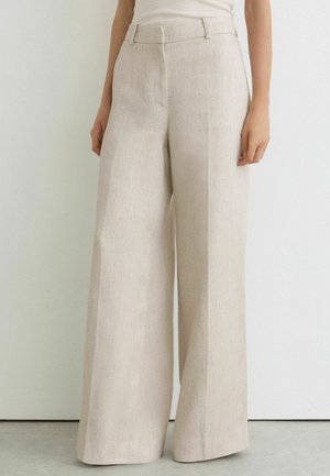 Beige hoch taillierte Weitbein-Hose mit Gürtelschlaufen, getragen mit einem in die Hose gesteckten ärmellosen Top, von der Taille bis zum Boden gezeigt.