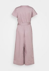 Combinaison rose clair à manches courtes, taille cintrée avec ceinture, jambes larges, tissu texturé. Design dos sans couture sans fermetures visibles.